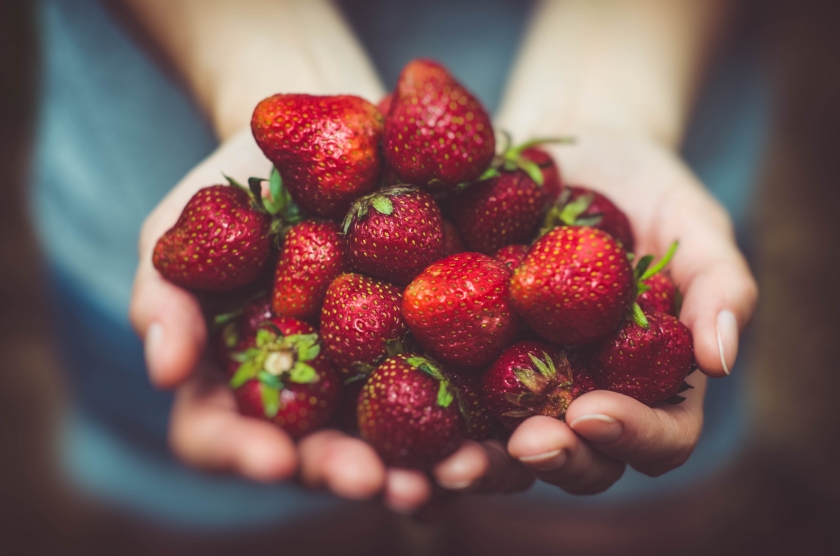 A woman holds strawberries in her hands.