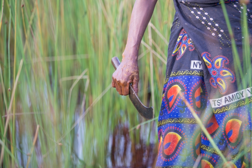 A woman holds a small machete in a field in Madagascar
